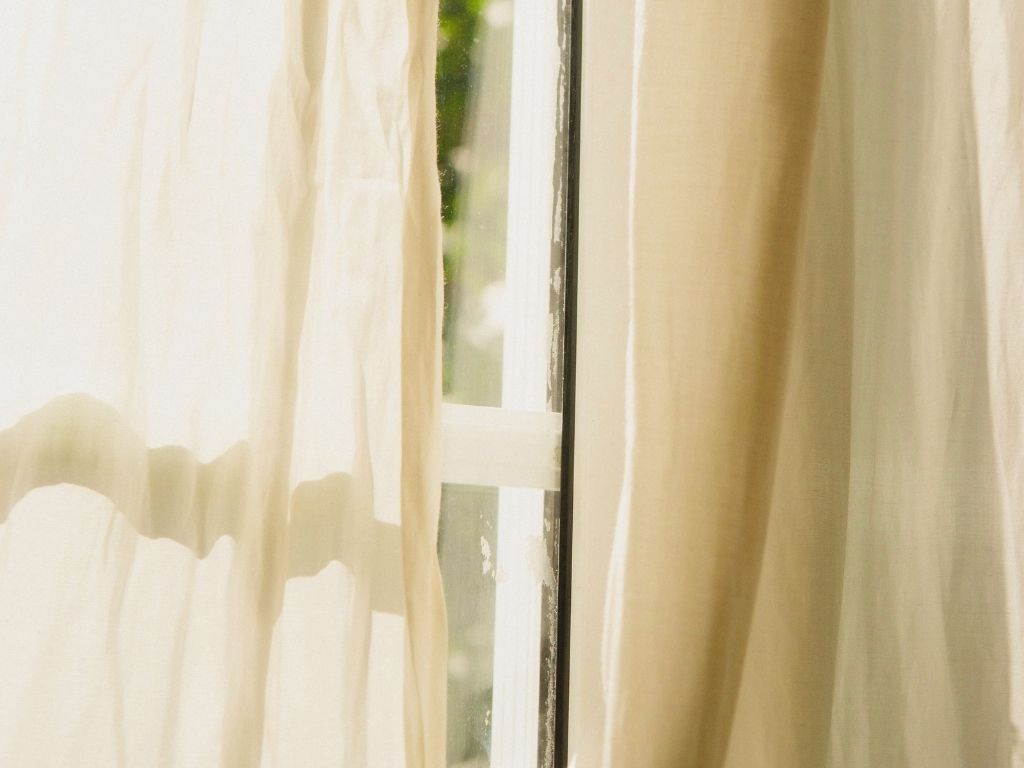 A sheer curtain moving in soft window light