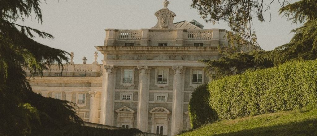 Neoclassical stone building seen across a lawn between trees