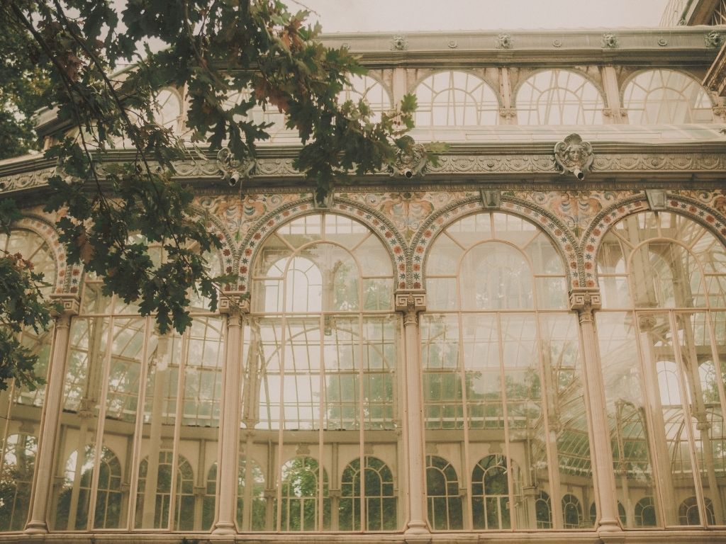 A row of tall arched glasshouse windows seen from a courtyard