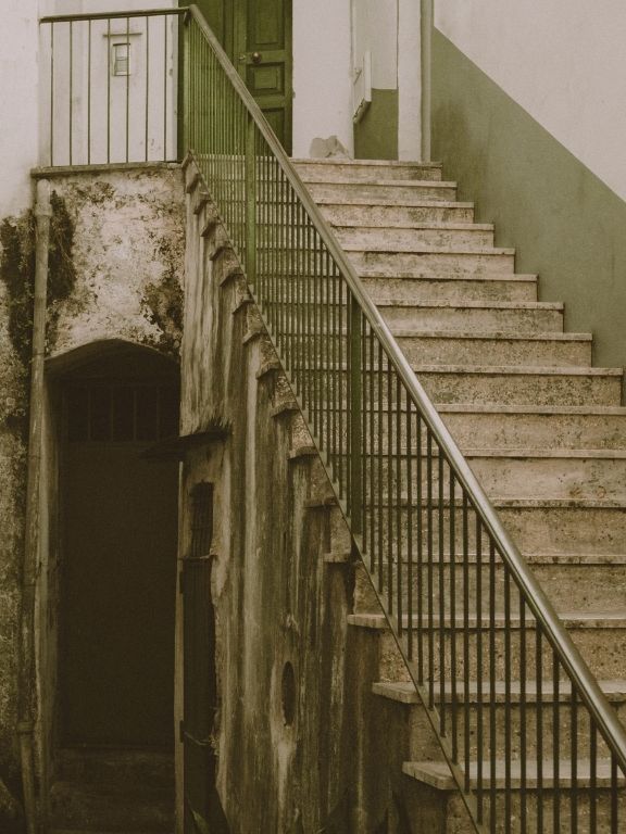 A stone stair climbing past a planted wall in afternoon light